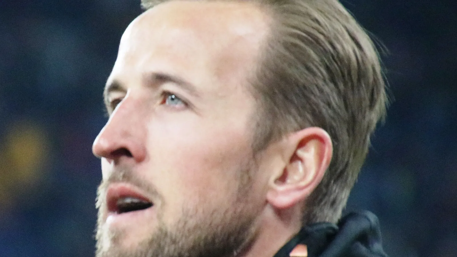 Close view of England striker Harry Kane in a Bayern Munich jacket before a match under stadium lights
