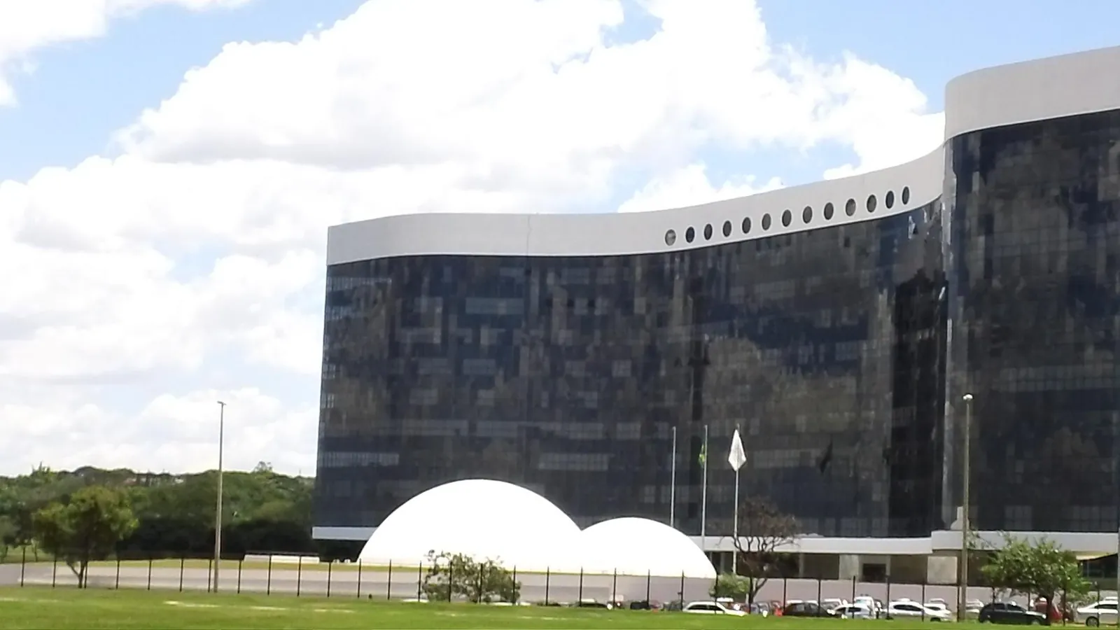 A sede do Tribunal Superior Eleitoral em Brasília, com fachada curva de vidro preto e duas cúpulas brancas à frente