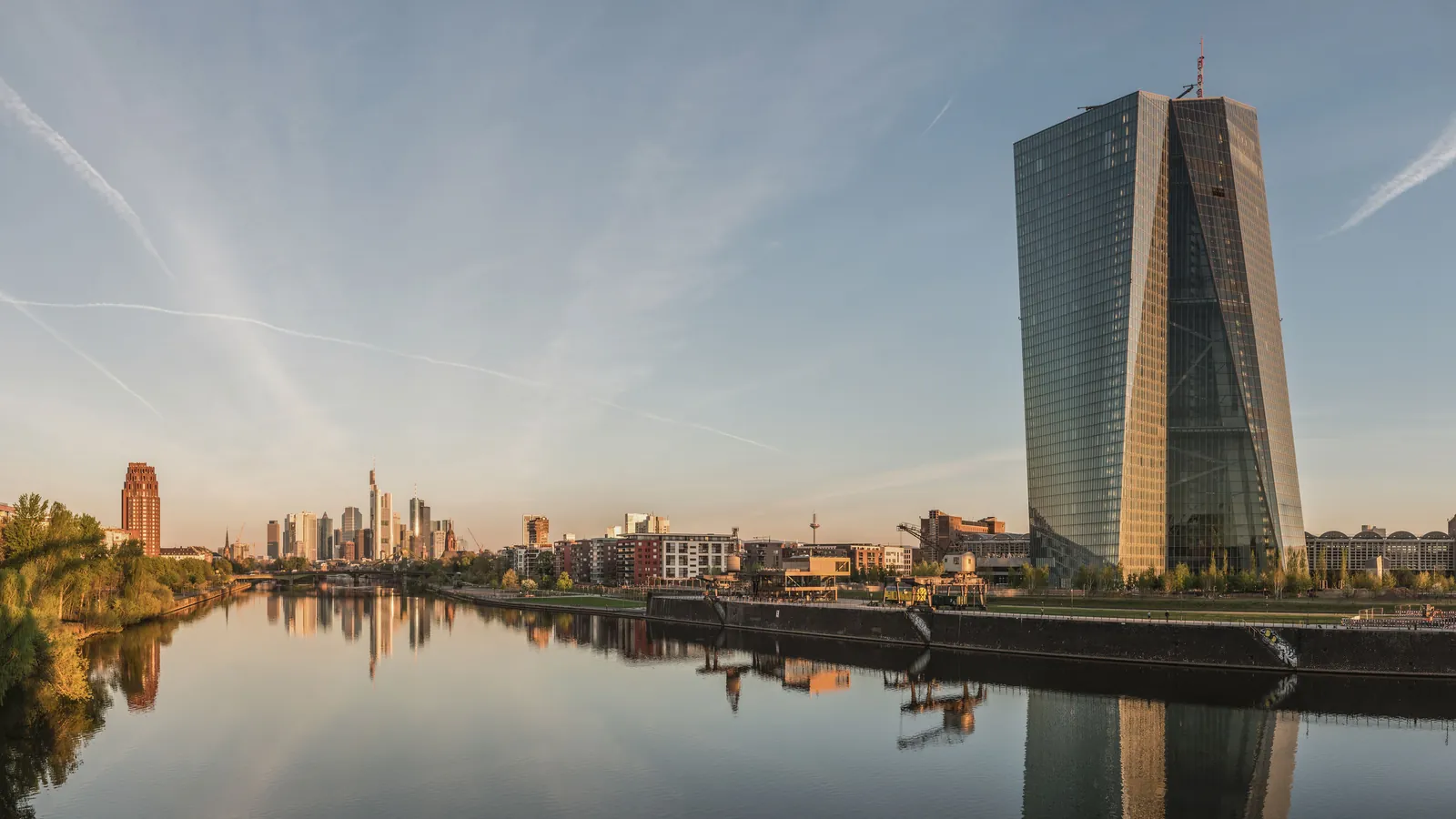 The European Central Bank tower beside the river Main at dawn, the Frankfurt skyline behind it