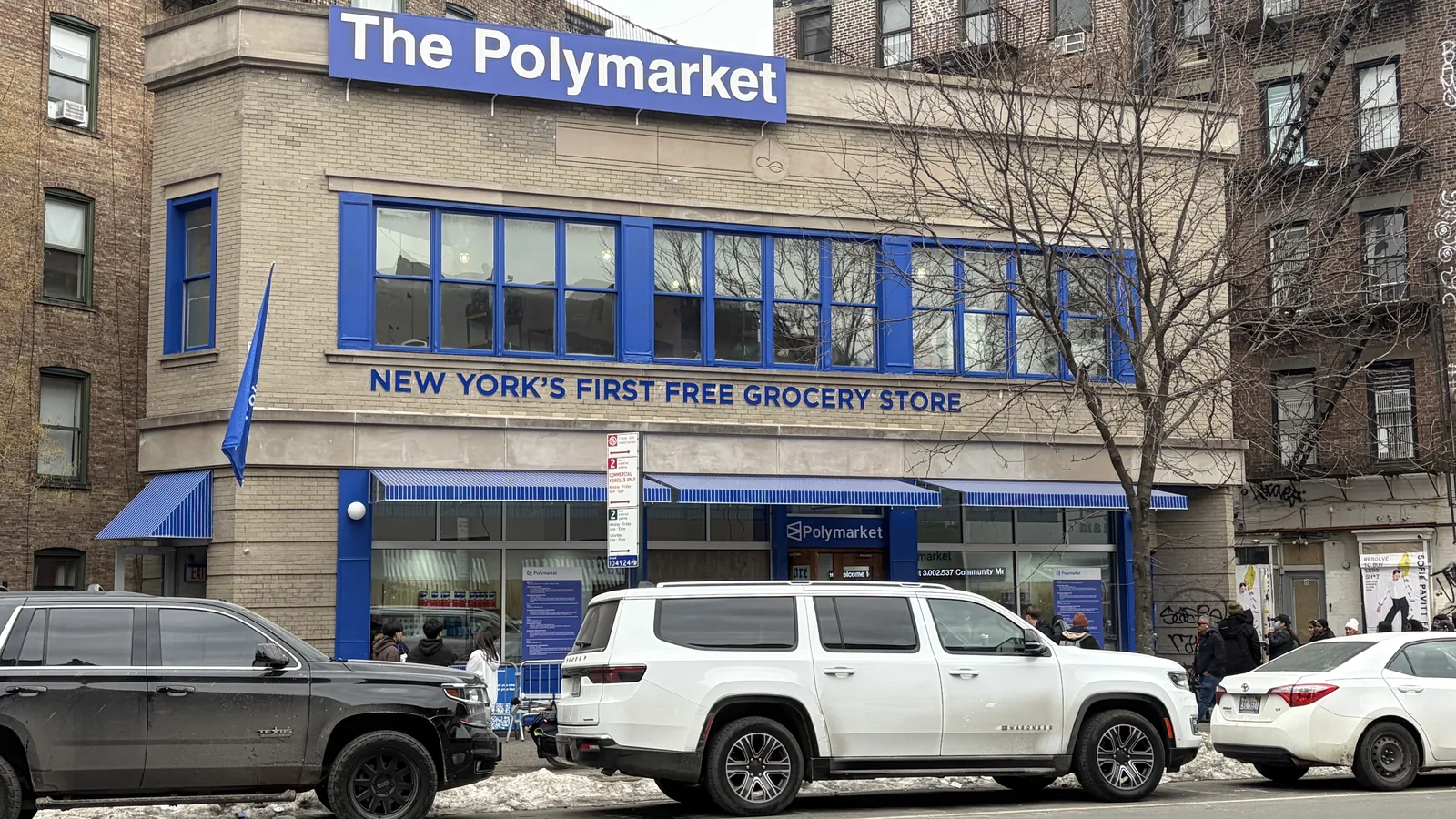 A corner shop in New York with a blue sign reading The Polymarket, New York's first free grocery store