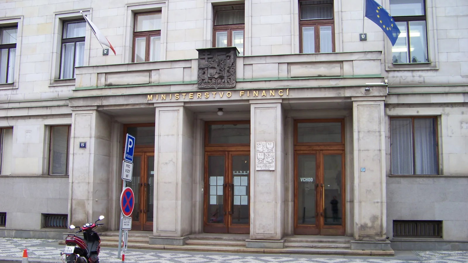 Stone entrance of the Czech Ministry of Finance in Prague, with the Czech and European flags above the doors