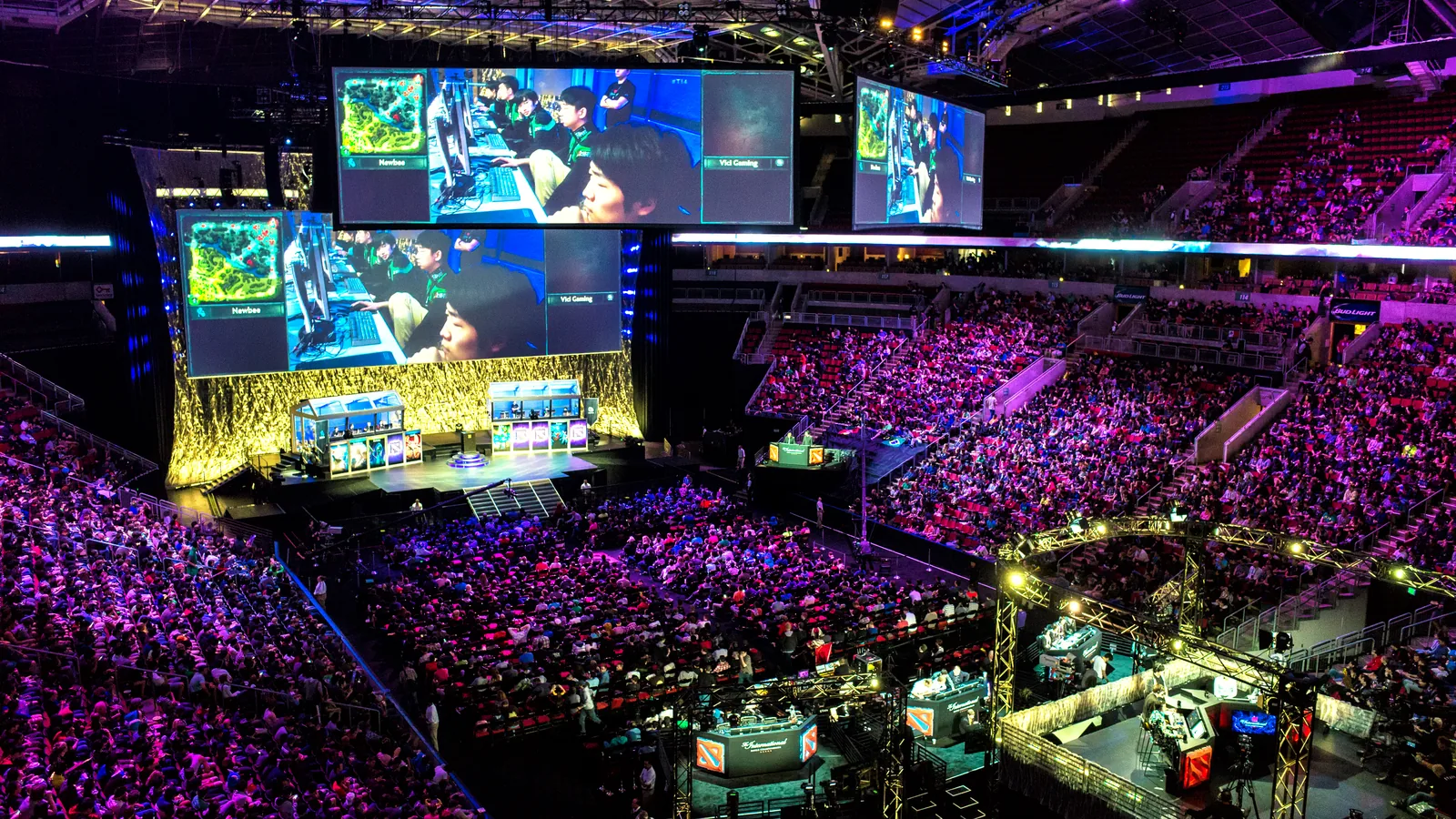 A full arena watching a Dota 2 match on large screens above the stage at The International in Seattle