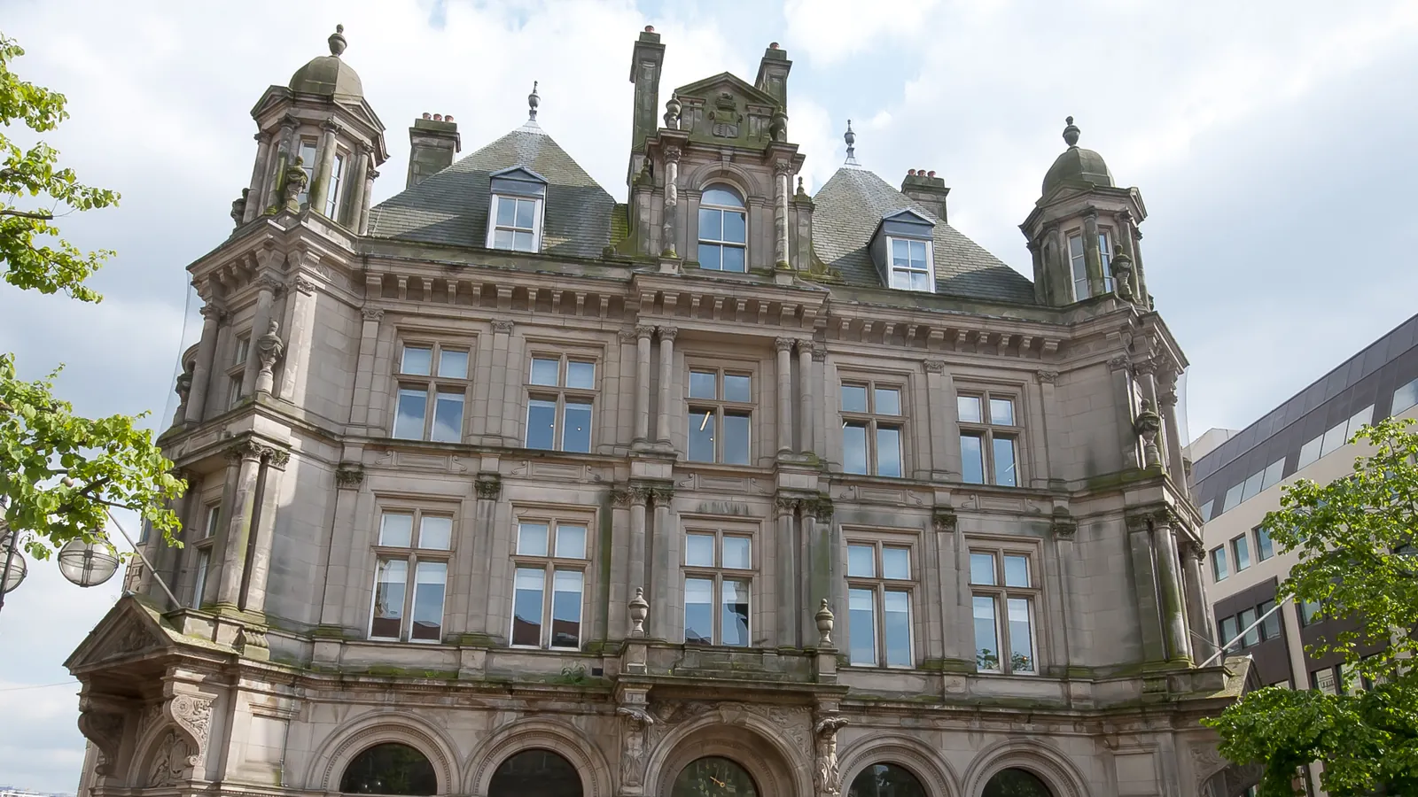 The ornate stone front of Victoria Square House in Birmingham, a former post office with corner turrets and a slate roof